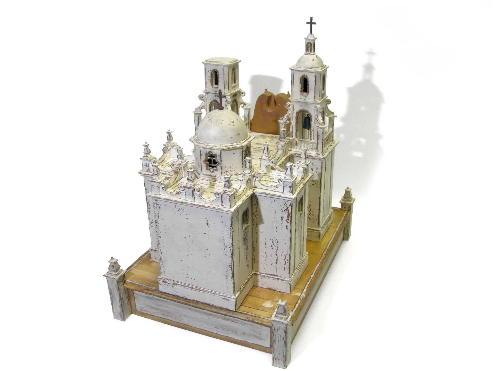 Mission San Xavier del Bac sculpture from the left, showing the domed chapels and the low courtyard wall.